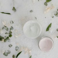 pexels-photo-6690234-6690234 Flat lay of cosmetic cream jars surrounded by natural leaves and petals, perfect for beauty product promotions.